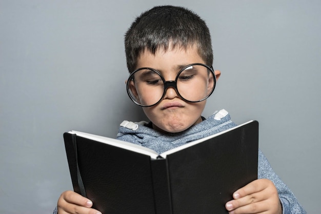 Étudiant, Garçon aux lunettes géantes lisant un livre avec des gestes drôles et variés