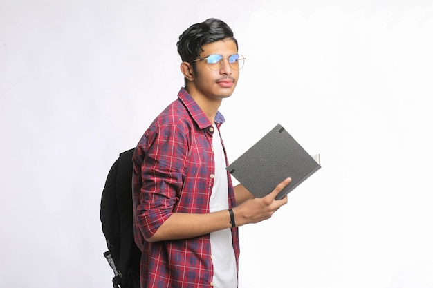 Étudiant indien debout avec sac et lecture de produits laitiers sur fond blanc.