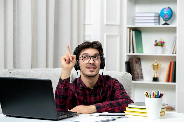 Étudiant en ligne jeune homme en chemise à carreaux avec des lunettes étudiant sur ordinateur dans les écouteurs