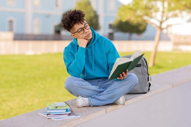 Étudiant avec un livre contemplant sur le campus