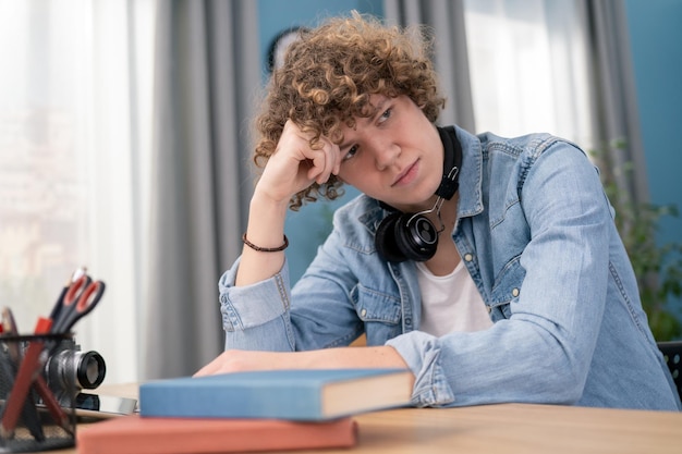 Étudiant masculin concentré dans le casque s'asseoir à l'étude de bureau prenant des notes homme concentré dans les écouteurs writin