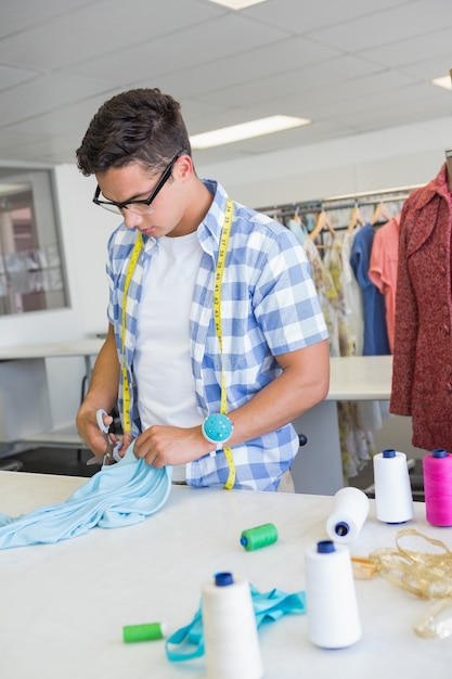 Étudiant de mode coupe tissu avec une paire de ciseaux