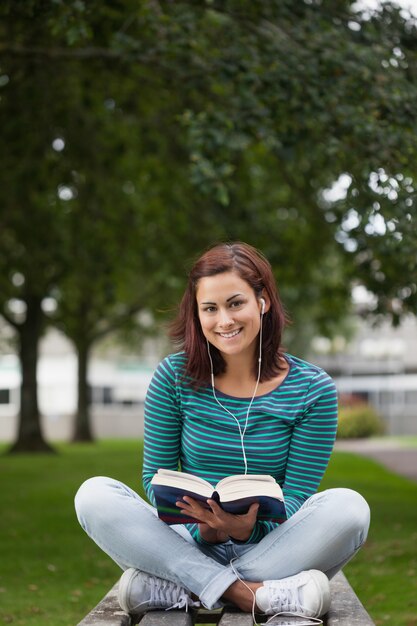 Étudiant occasionnel souriant, assis sur un banc de lecture