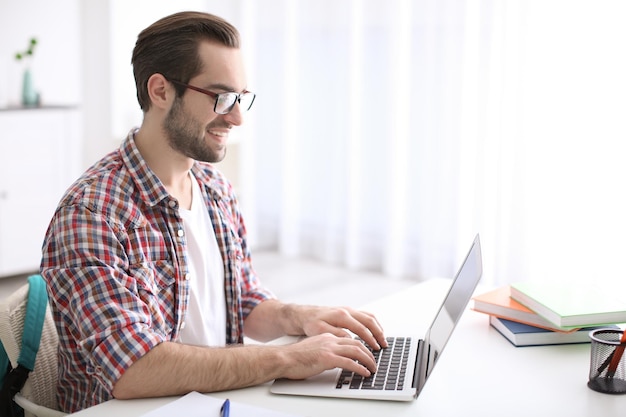 Étudiant avec ordinateur portable étudiant à table à l'intérieur