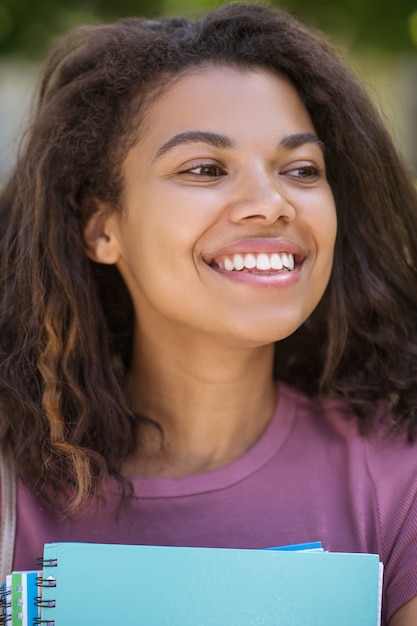 Étudiant. Une photo d'une fille en t-shirt rose tenant des manuels dans ses mains