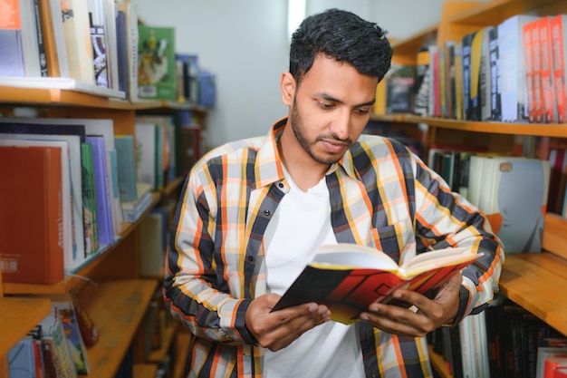 Étudiant ou pigiste arabe ou indien intelligent dans des vêtements décontractés élégants à la bibliothèque