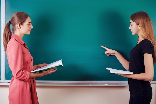 Étudiant avec professeur se tenir dans la salle de classe au tableau noir.