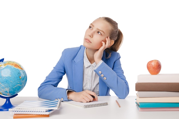 Étudiant réfléchi assis avec de nombreux livres avec sa tête dans la main isolé sur fond blanc