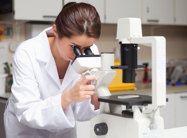 Étudiant en sciences féminines à la recherche dans un microscope