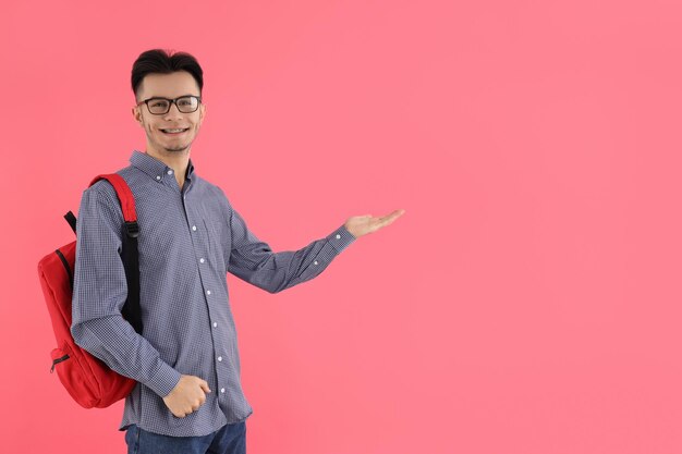 Étudiant de sexe masculin avec sac à dos sur fond rose