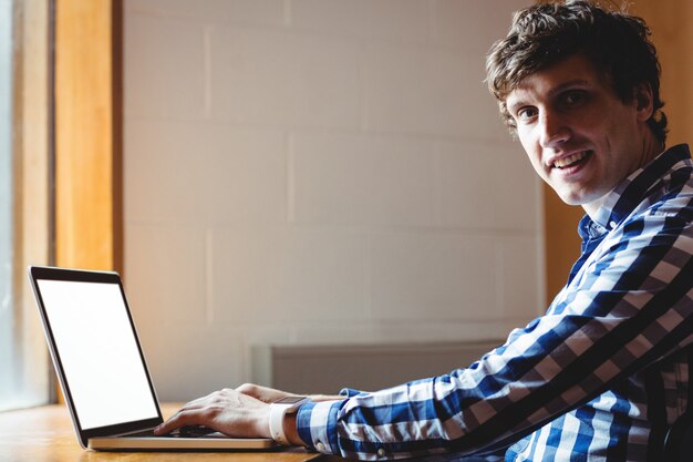 Étudiant souriant à l'aide d'un ordinateur portable au Collège