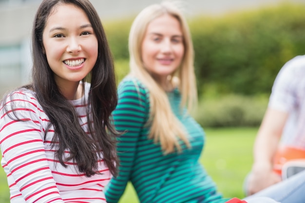 Étudiant souriant avec ami flou assis dans le parc