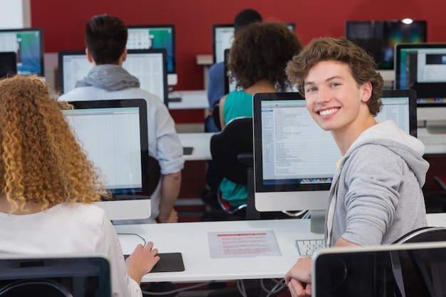 Étudiant en souriant à la caméra en cours d&#39;informatique