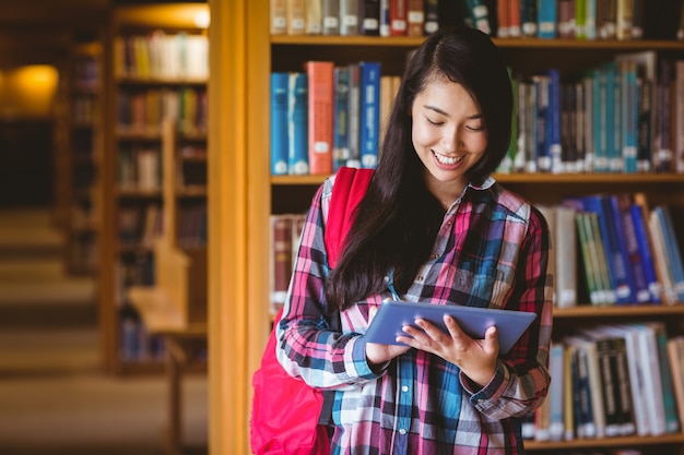 Étudiant souriant dans la bibliothèque avec tablette