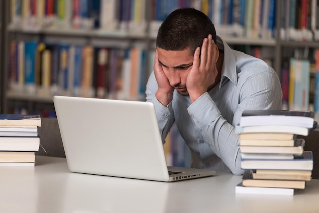 Étudiant stressé du lycée assis au bureau de la bibliothèque faible profondeur de champ