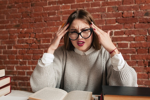 Étudiant stressé fatigué assis au bureau avec des livres