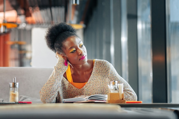 Étudiant de troisième cycle. Étudiant de troisième cycle intelligent aux cheveux noirs et bouclés étudie dur dans la cafétéria