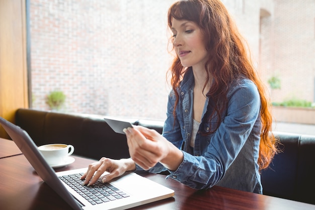 Étudiant utilisant un ordinateur portable au café pour faire des achats en ligne