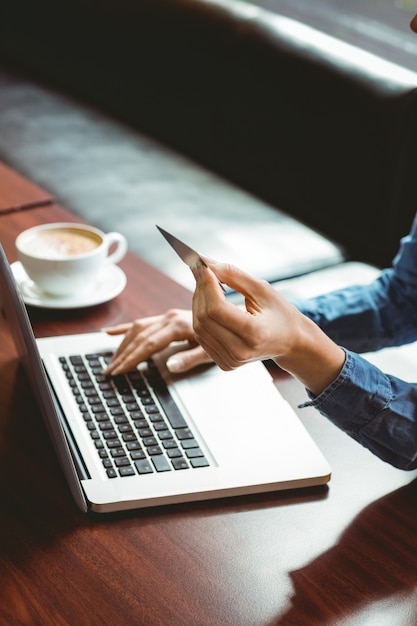 Étudiant utilisant un ordinateur portable au café pour faire des achats en ligne