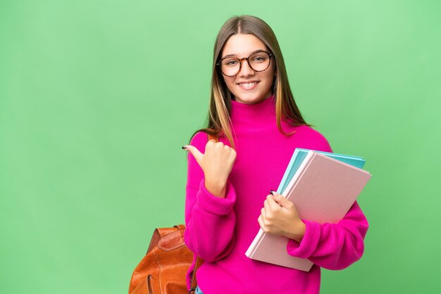 Étudiante adolescente caucasienne sur fond isolé pointant vers le côté pour présenter un produit