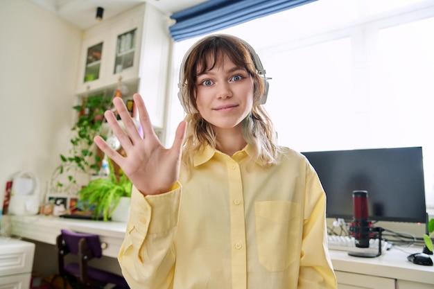 Étudiante adolescente dans des écouteurs sans fil parlant en regardant la caméra