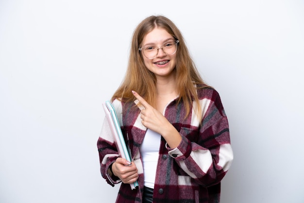 Étudiante adolescente fille russe isolée sur fond blanc pointant vers le côté pour présenter un produit