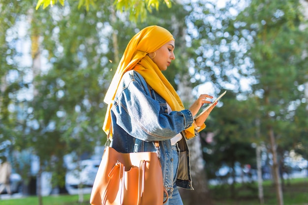 Étudiante arabe. Belle étudiante musulmane portant un hijab jaune vif tenant une tablette.