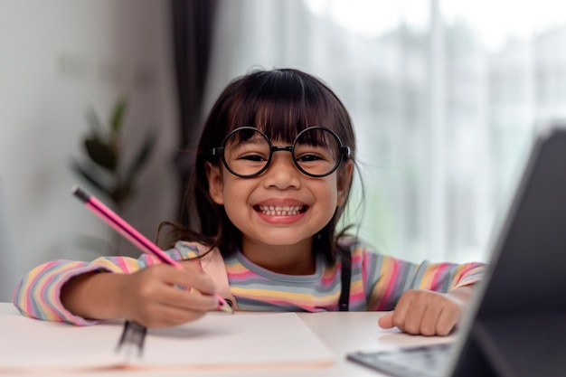 Étudiante asiatique en ligne apprenant en classe étudier en ligne avec l'enseignant Une fille heureuse apprend l'anglais en ligne avec une tablette à la maison Nouveau normalCovid19 coronavirusDistanciation sociale rester à la maison