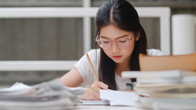 Étudiante asiatique lisant des livres dans une bibliothèque à l'université