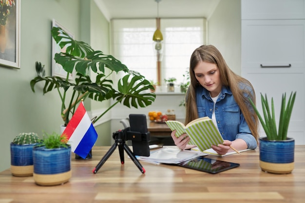 Étudiante assise à la maison étudiant en ligne en regardant la webcam du smartphone