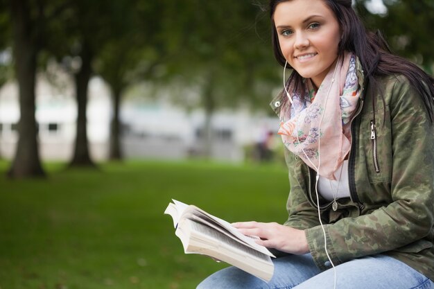 Étudiante brune joyeuse assis sur un banc de lecture