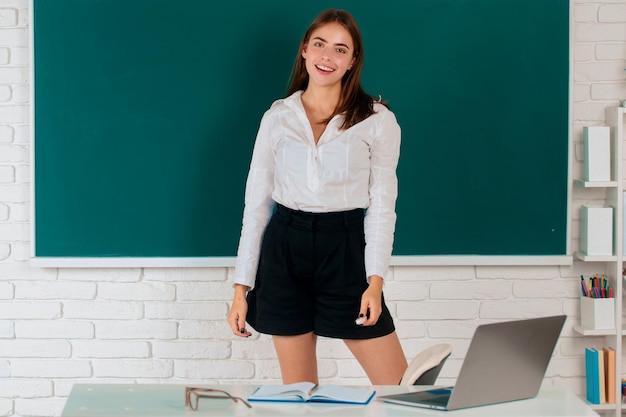 Étudiante debout sur fond de tableau noir dans l'enseignement universitaire