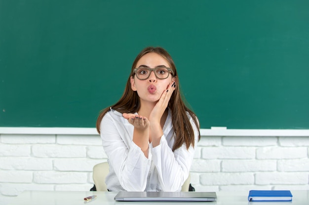 Étudiante drôle avec baiser d'air dans la salle de classe de l'école mignonne écolière