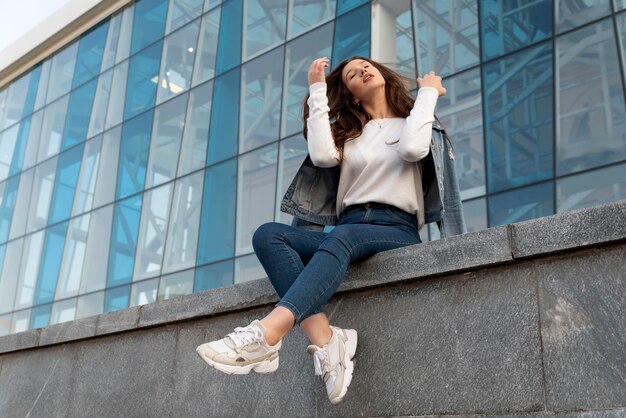 Étudiante élégante se reposant à l'intérieur et lissant ses cheveux Belle étudiante dans la rue de la ville d'été