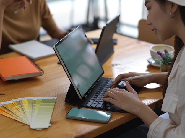 Étudiante faisant du projet de groupe tablette numérique blanche sur table en bois