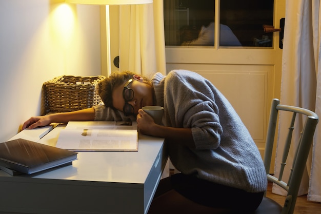 Étudiante fatiguée dort sur le bureau