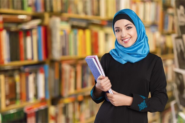 Étudiante de la jeune femme tenant un ordinateur portable dans la bibliothèque