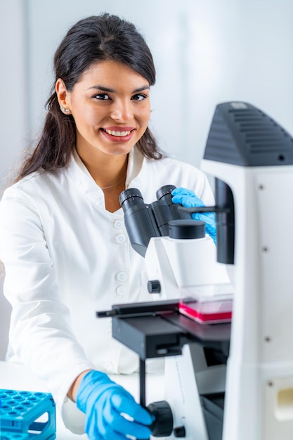 Étudiante en laboratoire plaçant le flacon de culture sur la scène d'observation au microscope