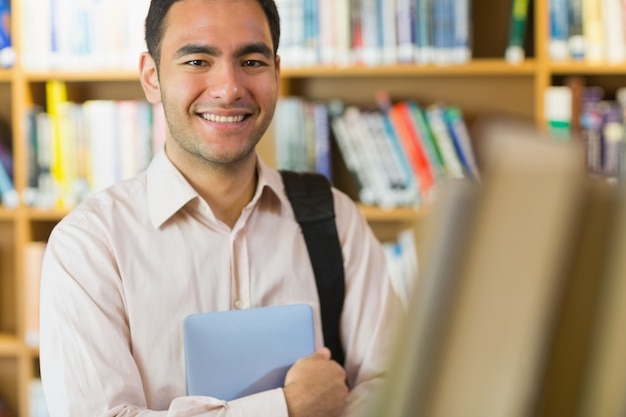 Étudiante mature souriante avec tablette dans la bibliothèque