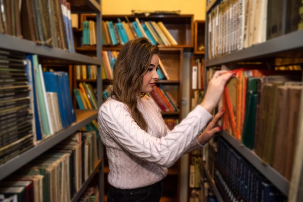 Étudiante à la recherche d'un livre dans une bibliothèque universitaire