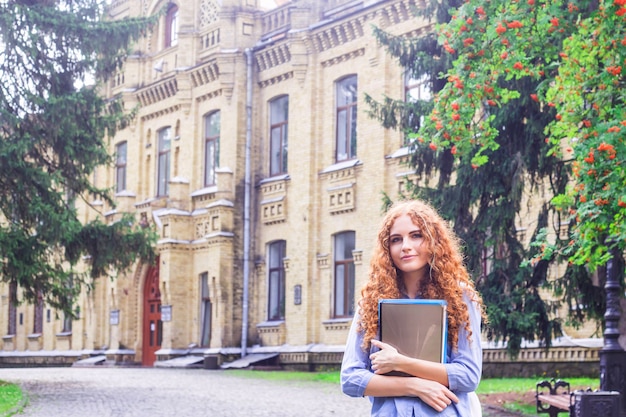 Étudiante rousse avec des dossiers et du matériel pédagogique à la main