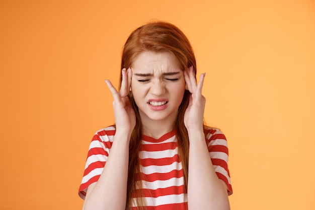 Étudiante rousse mignonne étourdie et mal à l'aise souffrant d'énormes maux de tête grincer des sourcils fronçant les sourcils serrer les dents painfu ...