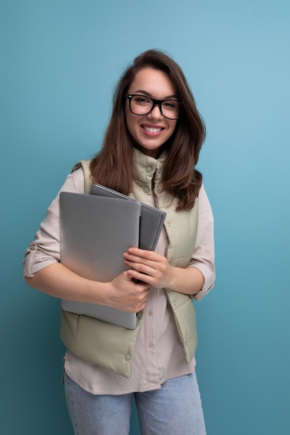 Étudiante s positive tenant des documents et un ordinateur portable sur fond d'espace vide