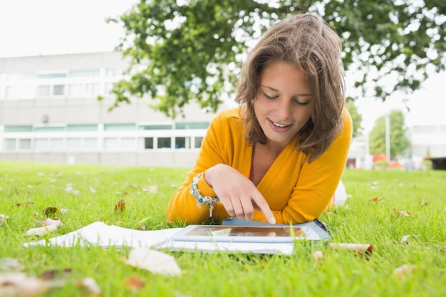 Étudiante souriante à l&#39;aide d&#39;une tablette PC dans la pelouse