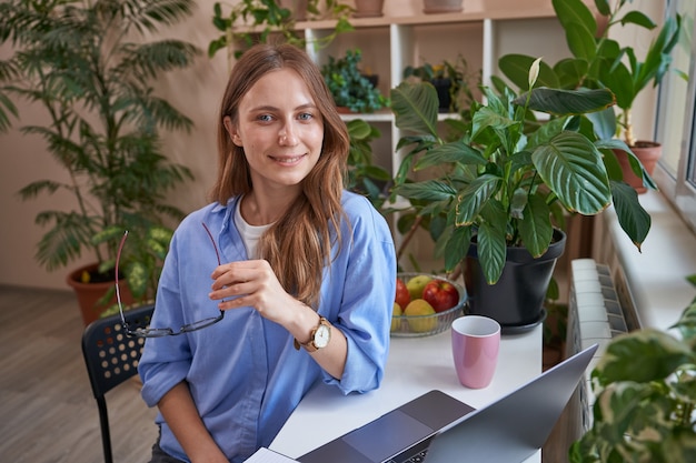 Étudiante souriante utilisant un ordinateur portable pendant les cours en ligne