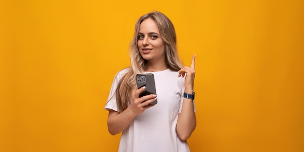 Étudiante avec un téléphone dans les mains sur fond jaune