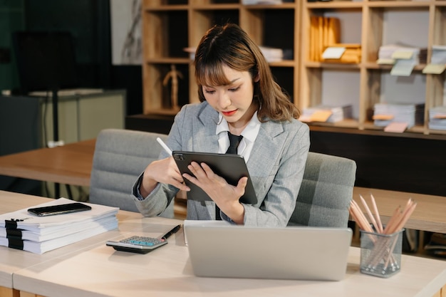 Étudiante universitaire asiatique se concentrant sur sa classe en ligne avec tablette et ordinateur portable