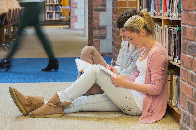 Étudiants assis devant une étagère