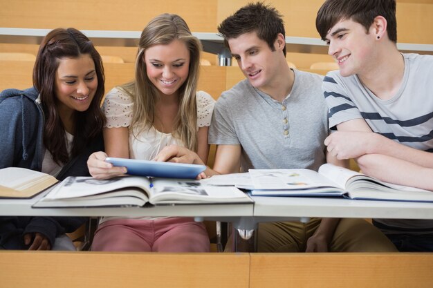 Étudiants assis regardant tablet pc et souriant