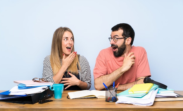 Étudiants avec beaucoup de livres avec une expression faciale surprise